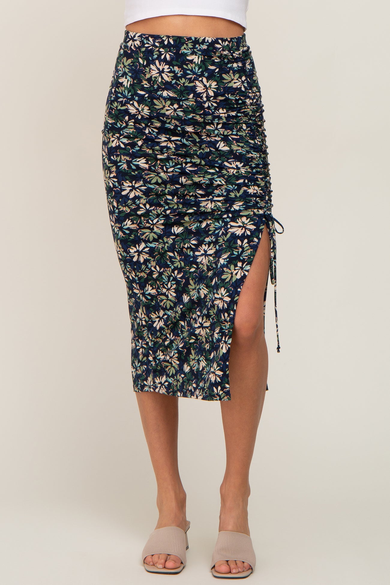 woman wearing a navy floral midi skirt with side ruching and a slit, paired with light beige sandals