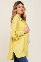 Pregnant woman wearing a yellow oversized button-down maternity shirt and blue jeans