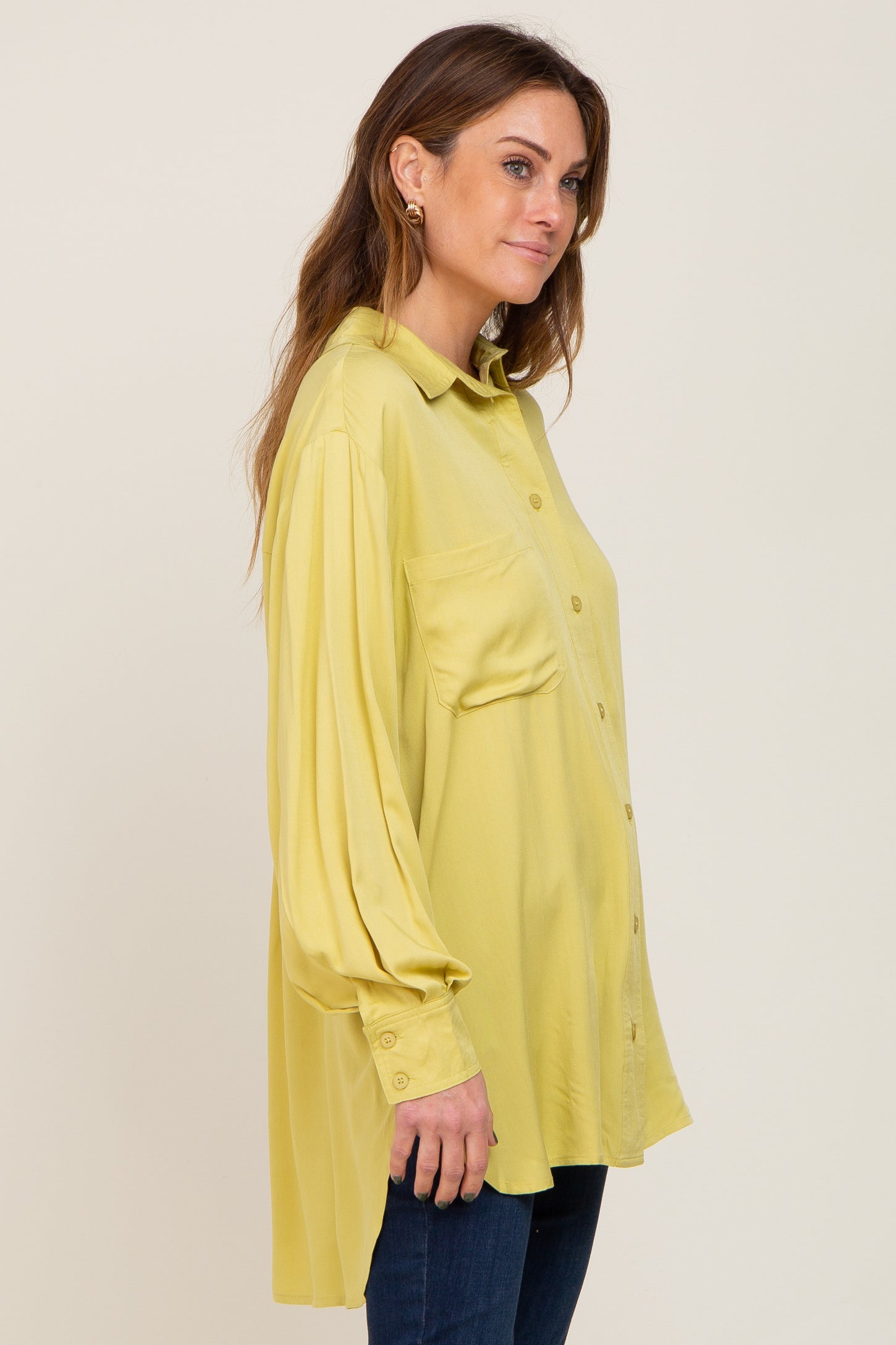 woman wearing a long sleeve yellow button down maternity shirt with a chest pocket and dark jeans