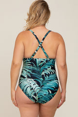 woman wearing a black tropical print maternity swimsuit with crisscross straps and a flattering back design