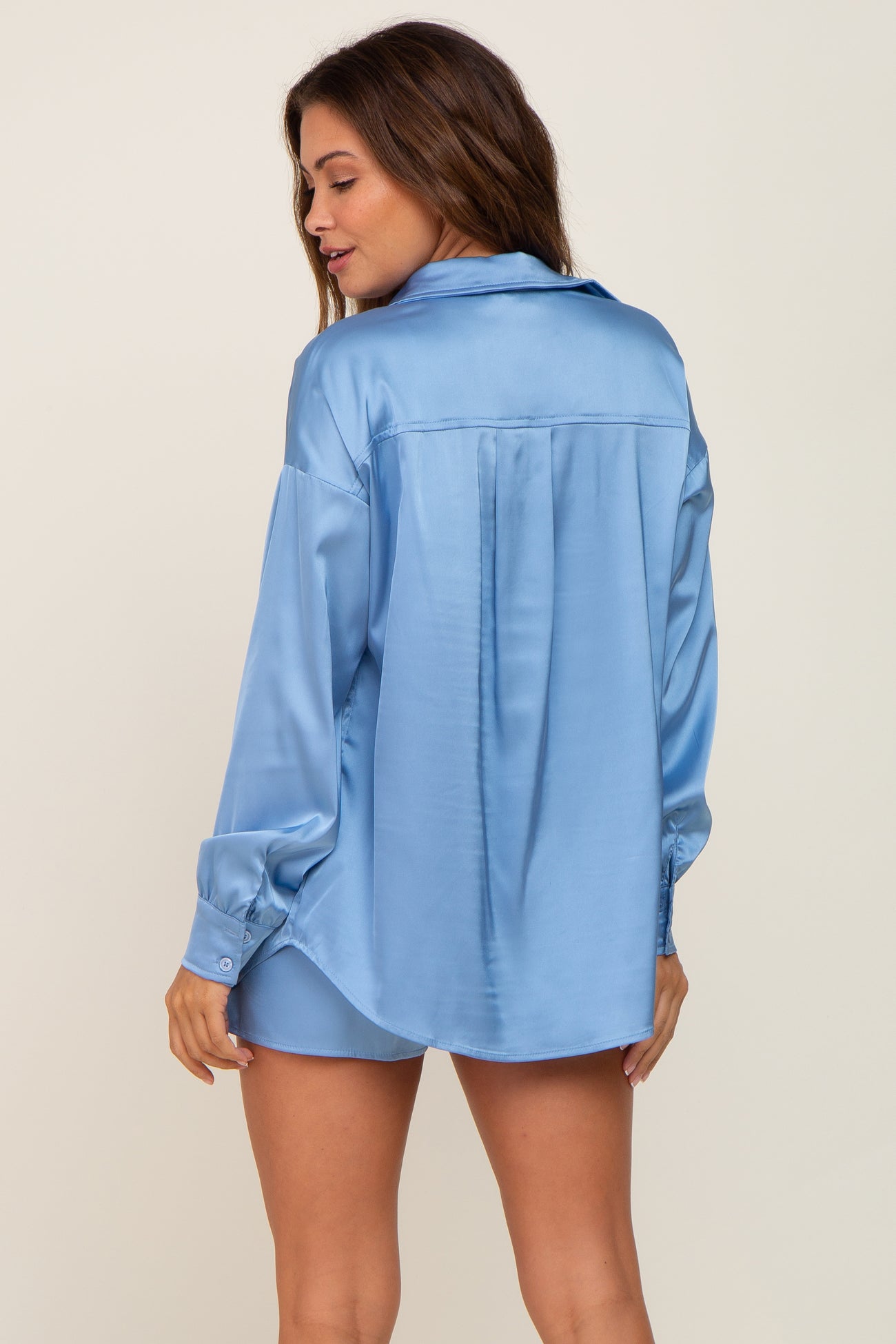 Woman wearing a light blue satin long sleeve button down shirt and matching shorts set