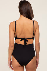 woman wearing a black maternity one-piece swimsuit with a tie-back closure and ribbed texture