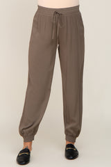 woman wearing taupe jogger pants with drawstring waist and elastic cuffs paired with black loafers