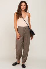 woman wearing beige camisole and olive green jogger pants with black crossbody bag and loafers