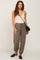 woman wearing beige camisole and olive green jogger pants with black crossbody bag and loafers