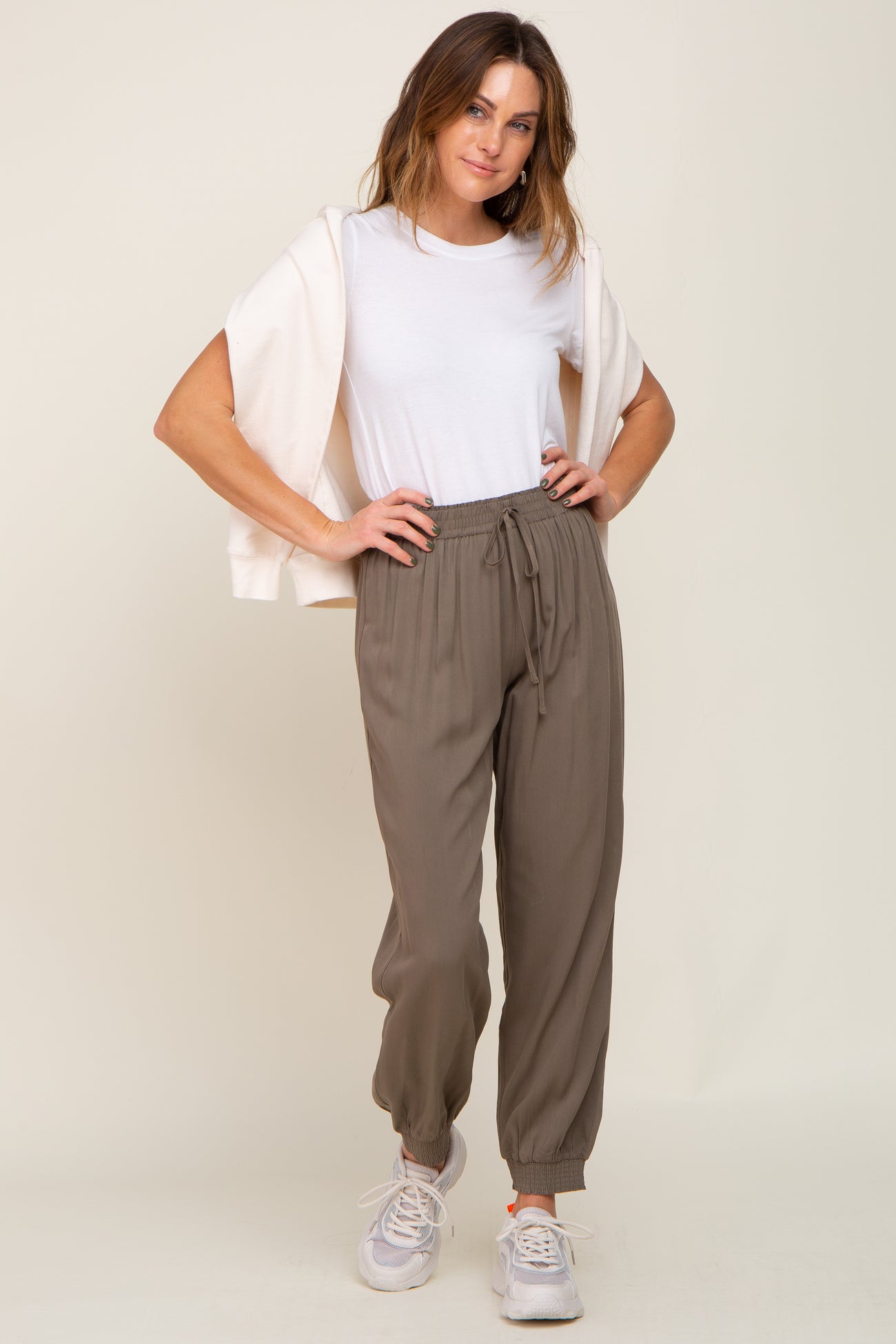 woman wearing olive green drawstring jogger pants with a white t-shirt and cream sweatshirt