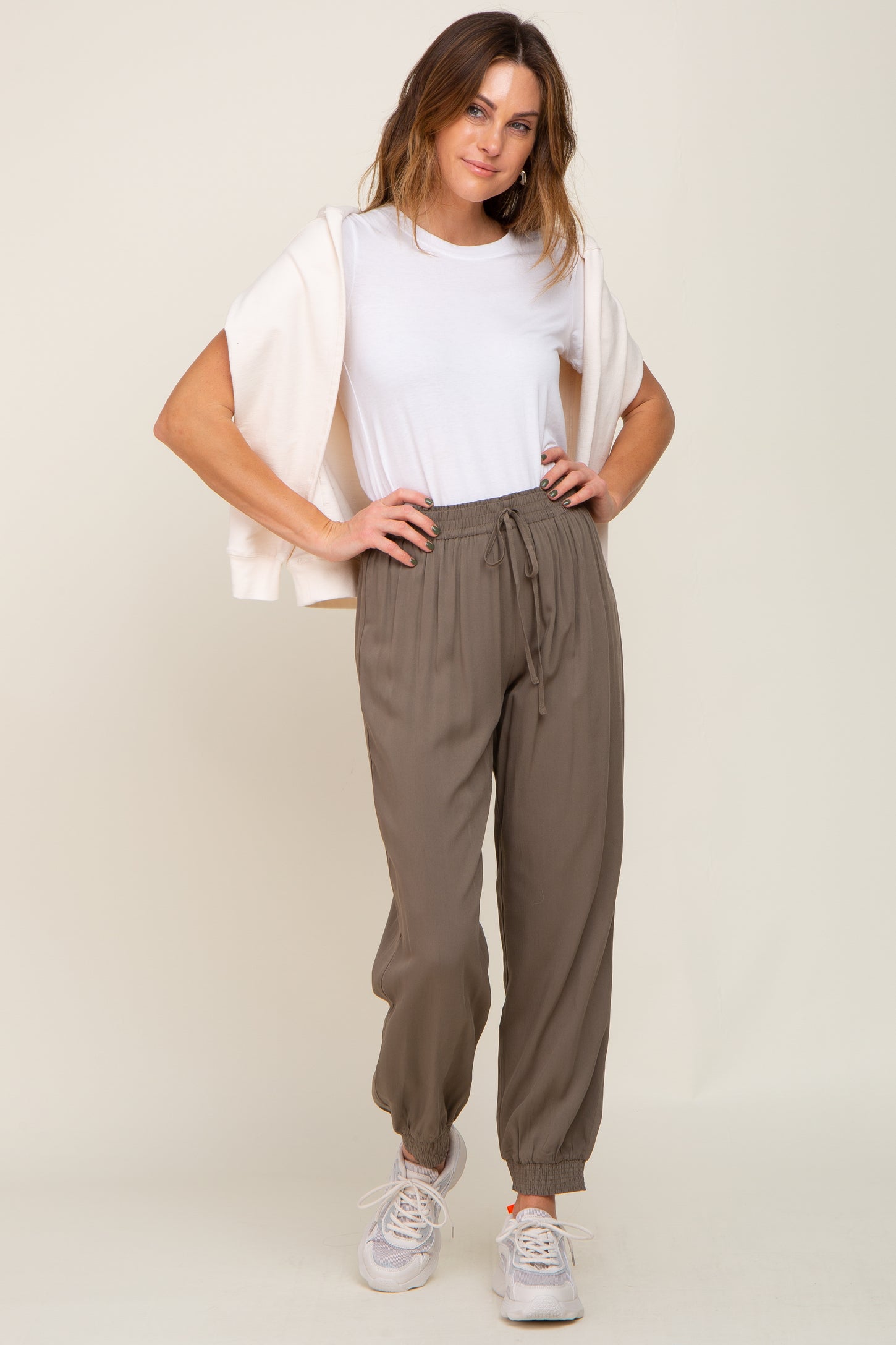 woman wearing olive green drawstring jogger pants with a white t-shirt and cream sweatshirt