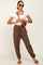 Woman wearing white crop top, brown jogger pants, and a brown crocodile texture crossbody bag