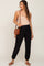 woman wearing black maternity joggers and a light beige tank top, carrying a brown crossbody bag