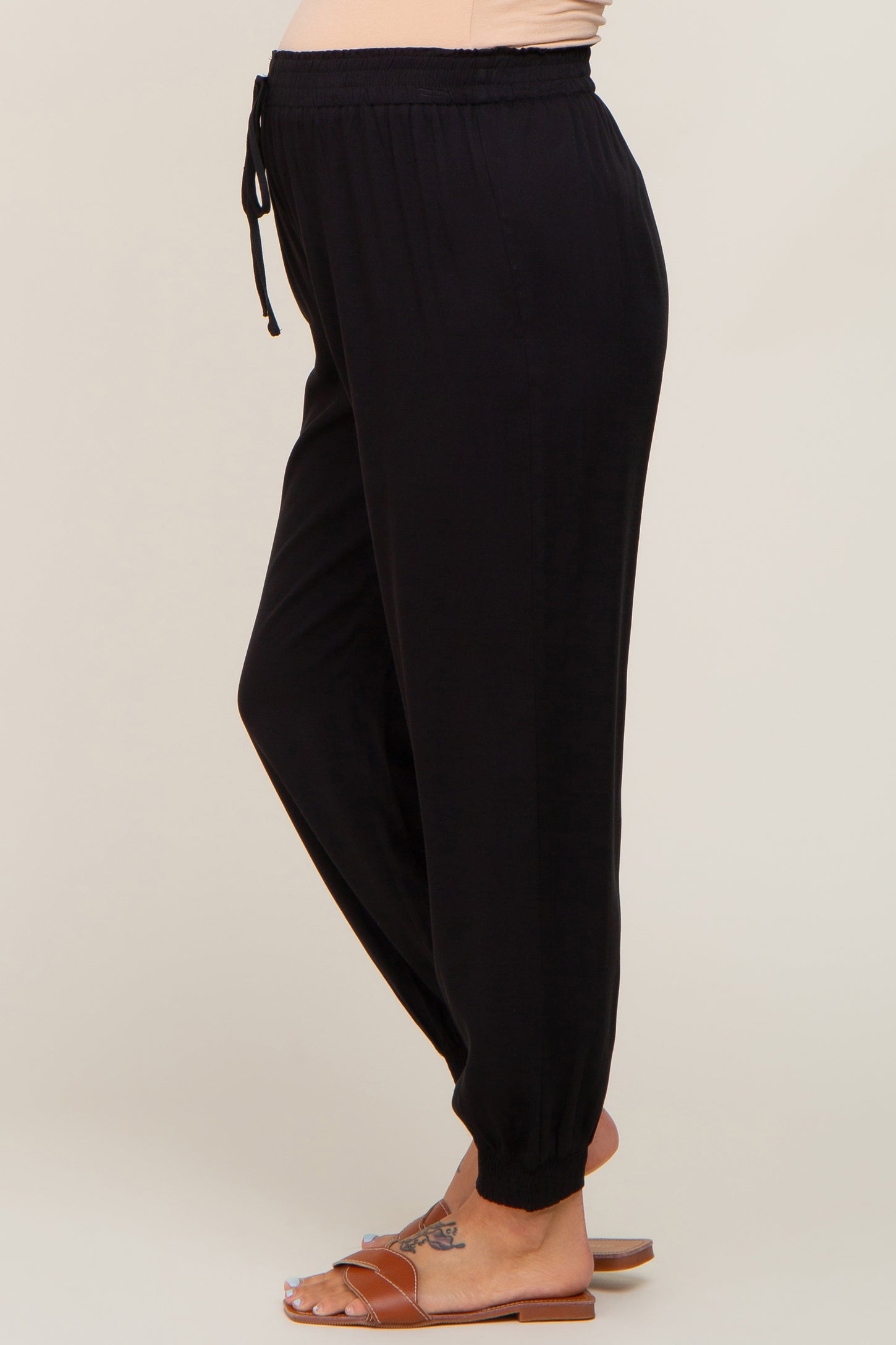 woman wearing black maternity jogger pants with a drawstring waist and tapered ankles, showing a baby bump