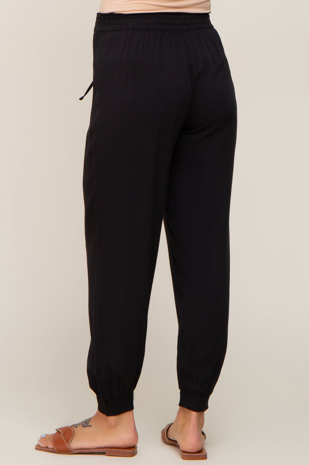 woman wearing black maternity jogger pants with an elastic waistband and gathered cuffs, seen from the back