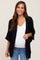Smiling pregnant woman wearing a black open-front maternity cardigan over a white top and blue jeans