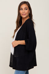 woman wearing a black open-knit maternity cardigan with three-quarter sleeves and a visible baby bump
