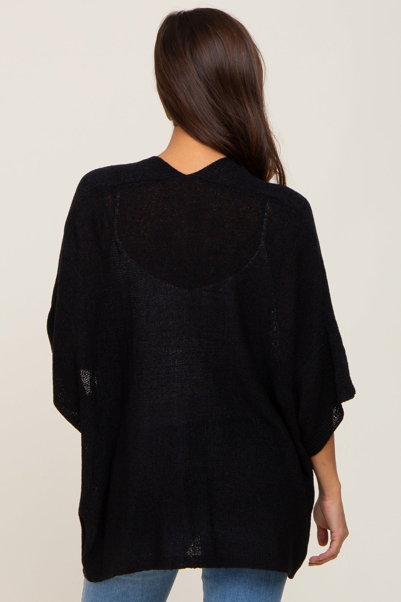 woman wearing a black loose-fitting maternity sweater with a knit design, seen from the back