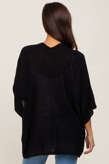 woman wearing a black loose-fitting maternity sweater with a knit design, seen from the back