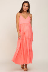 woman wearing a coral pink tiered maternity maxi dress with spaghetti straps
