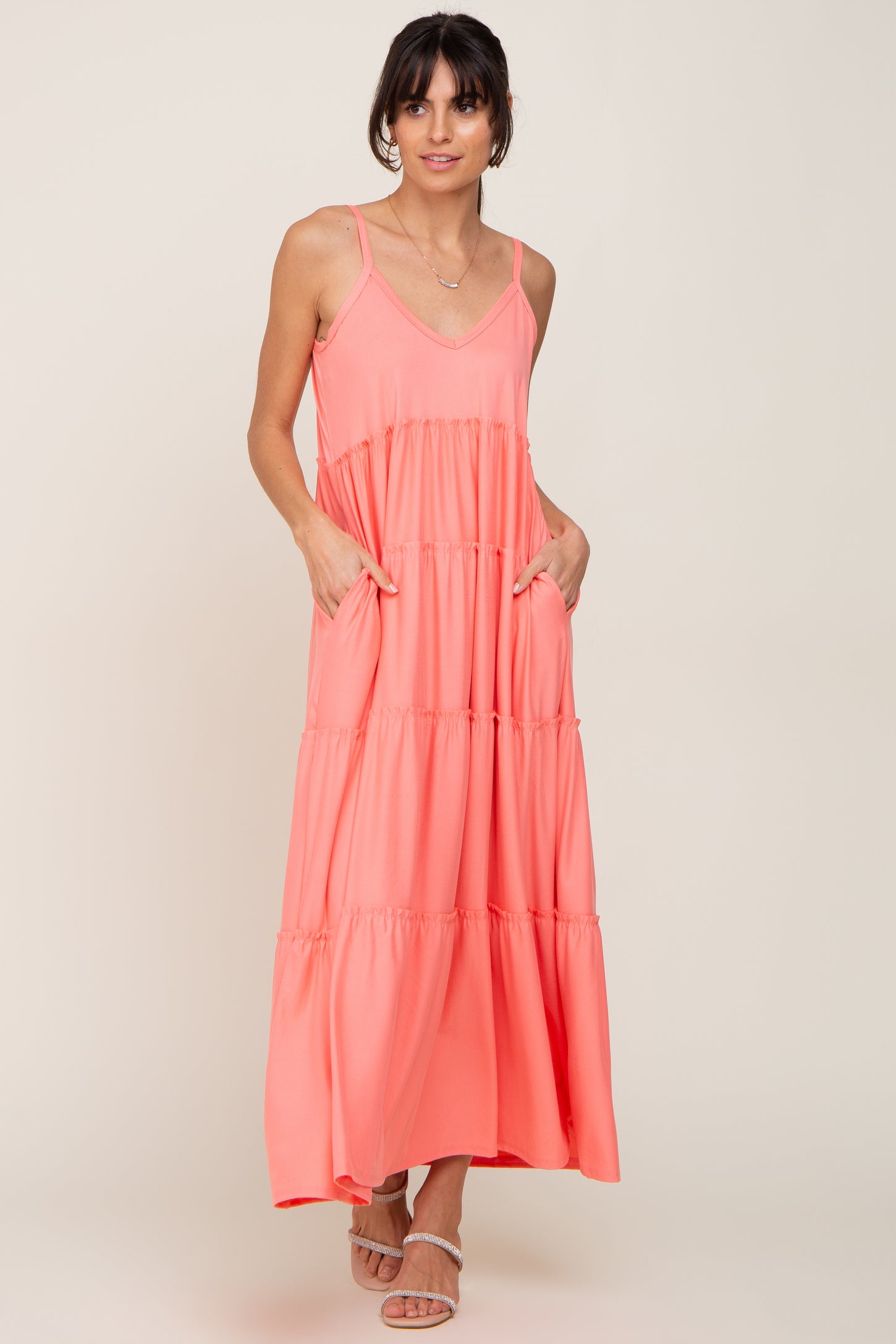 woman wearing a coral pink tiered maxi dress with spaghetti straps and pockets