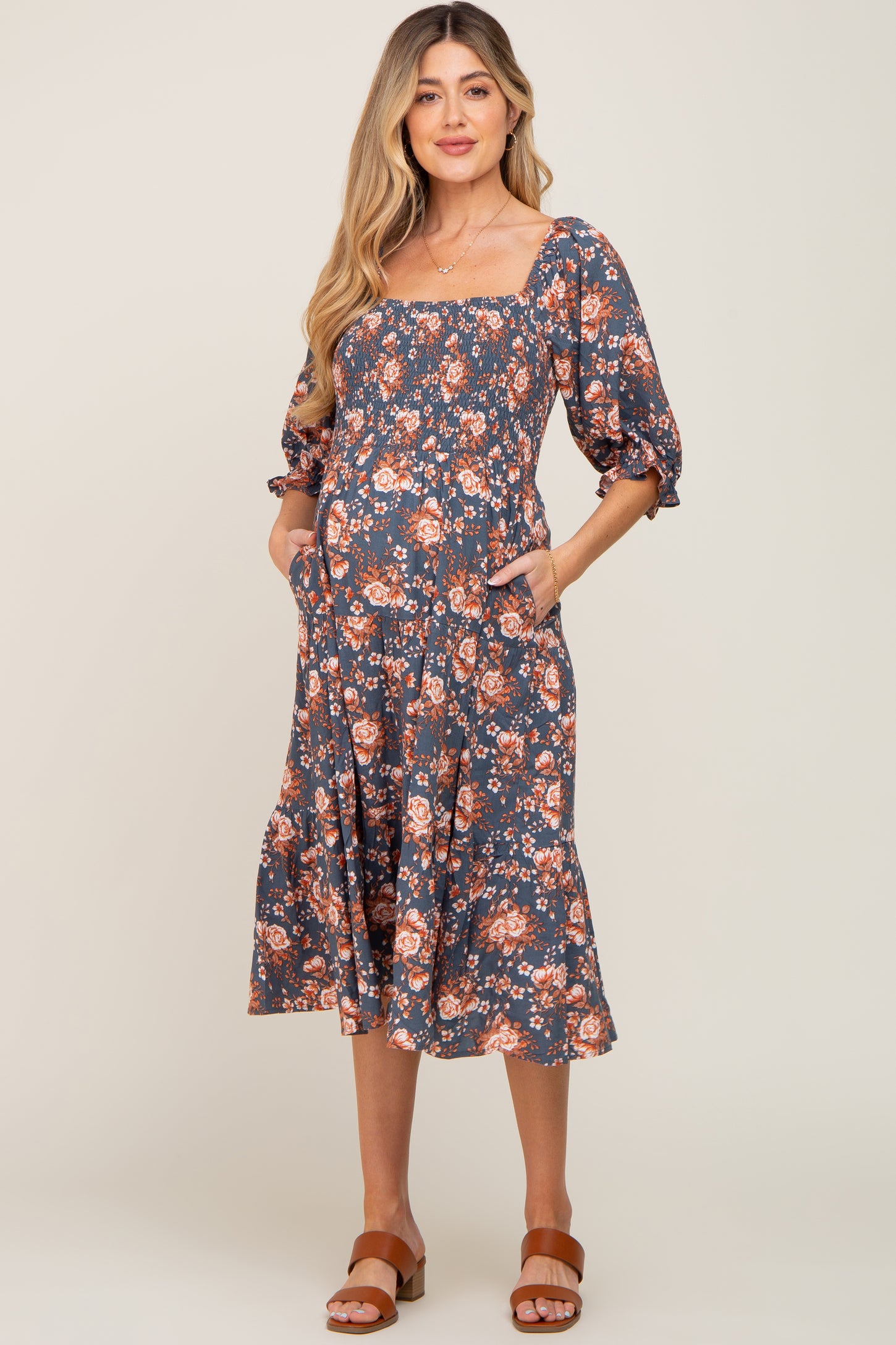 pregnant woman in a blue floral smocked maternity midi dress with pockets and square neckline