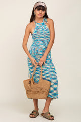woman wearing a multicolored halter neck midi dress and holding a woven tote bag