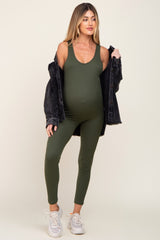 pregnant woman wearing olive green ribbed maternity jumpsuit and black denim jacket with white sneakers