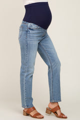 woman wearing light blue maternity jeans with a navy blue over-the-belly waistband and brown heeled sandals, showing baby bump