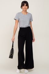 woman wearing a grey crew neck t-shirt and black wide-leg trousers holding a black handbag