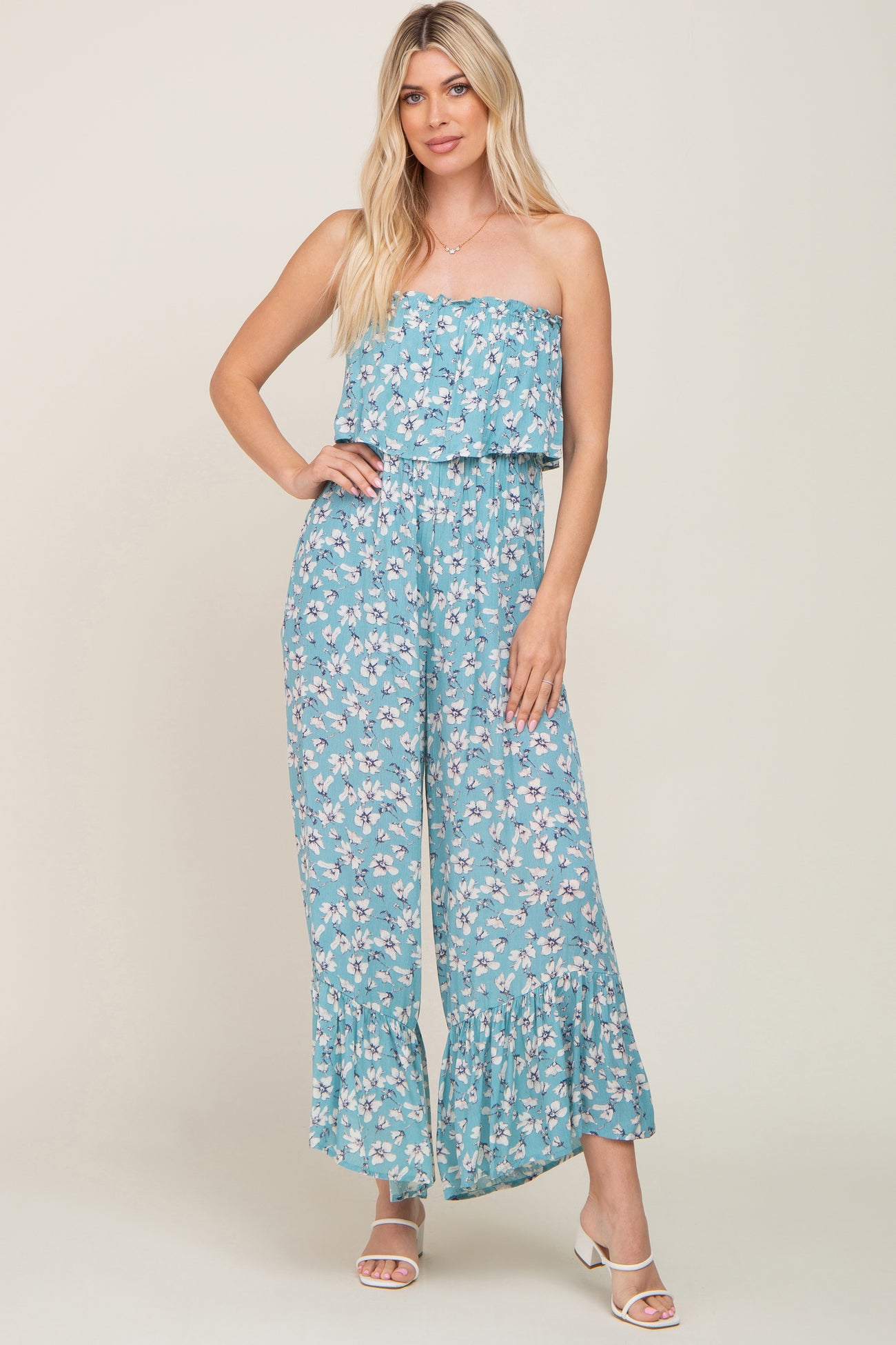 woman wearing a light blue strapless floral jumpsuit with wide legs and ruffle hem