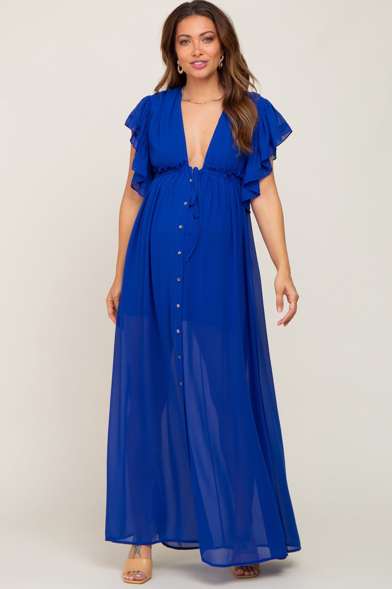 woman wearing a royal blue maternity maxi dress with ruffle sleeves and a deep v-neck, showcasing her baby bump