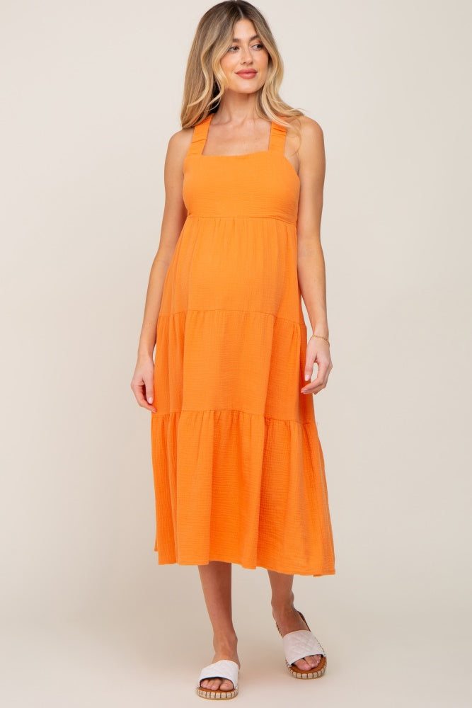 pregnant woman wearing an orange tiered maternity midi dress with square neckline and white sandals