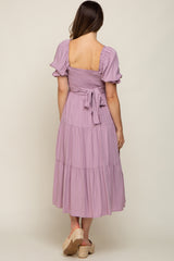 Back view of woman wearing a lavender tiered midi dress with smocked back and puff sleeves