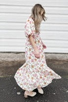 woman wearing a floral maxi dress with puff sleeves and flowing skirt walking outdoors