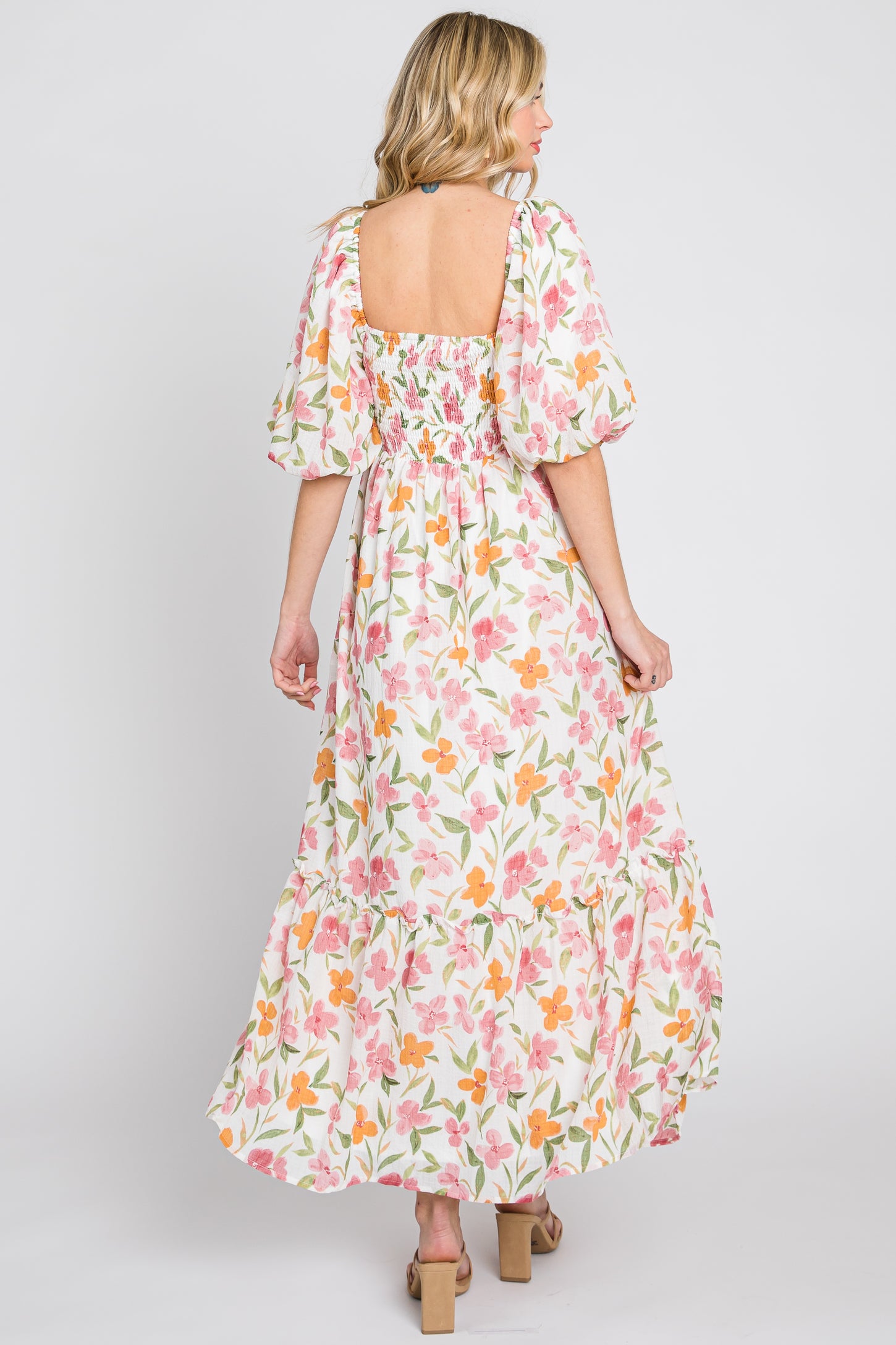 woman wearing a floral print maxi dress with puff sleeves and a square back, standing with her back to the camera