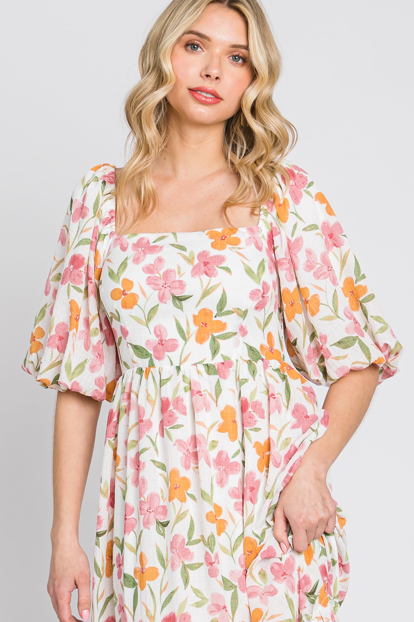 woman wearing a white floral puff sleeve midi dress with pink and orange flowers