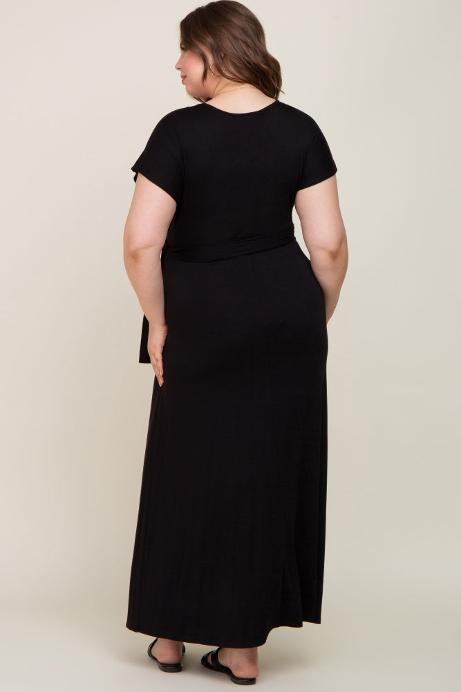Back view of a woman wearing a short sleeve black plus size maxi dress with a waist tie and black sandals