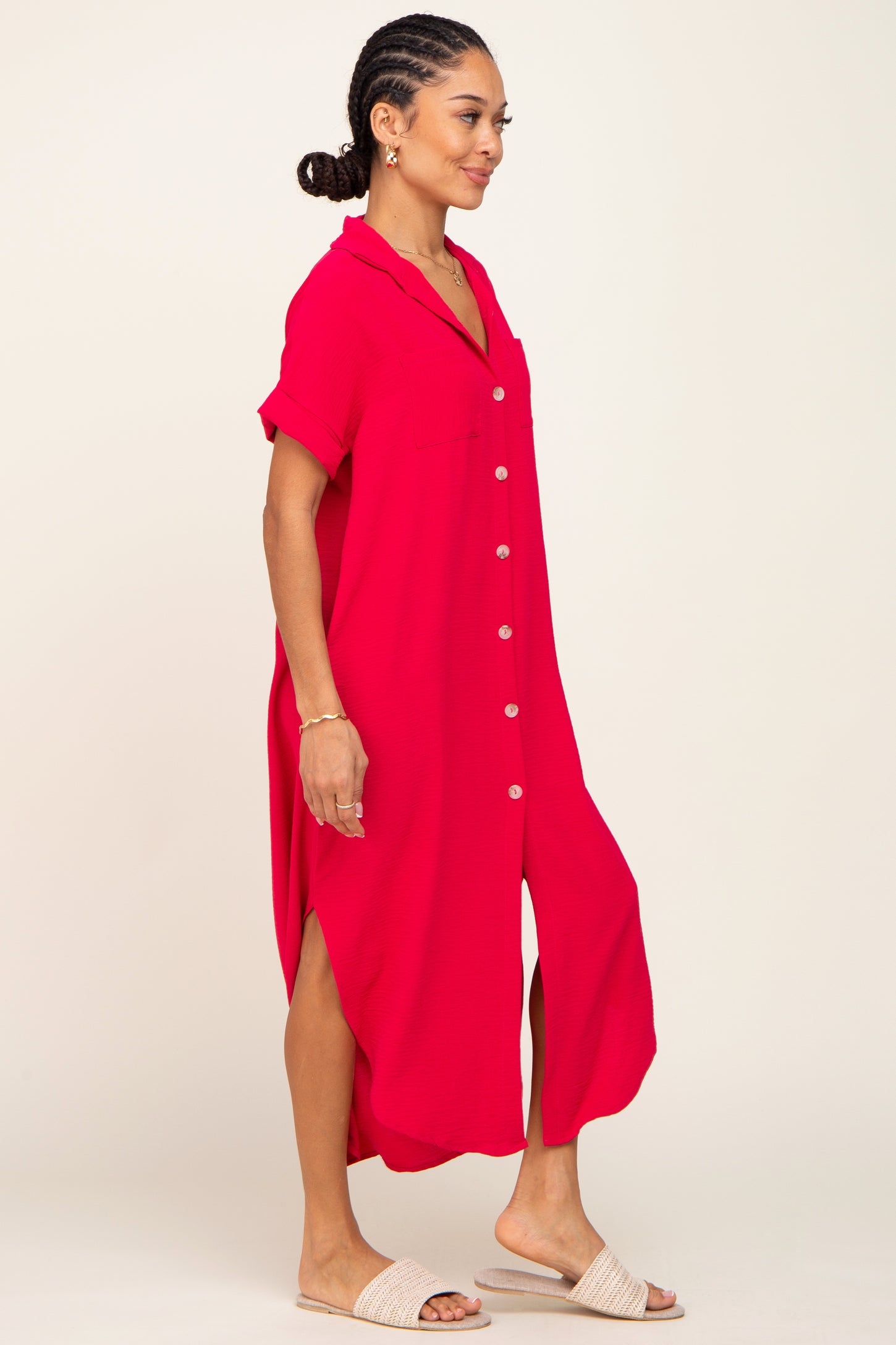 Woman wearing a bright red short sleeve button down midi dress with side slits and woven slide sandals