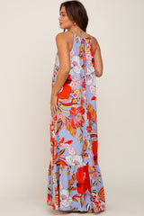 woman wearing a light blue floral halter maxi dress with red and orange flower patterns