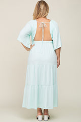 Back view of a woman wearing a light blue tiered maxi dress with an open back and tie detail