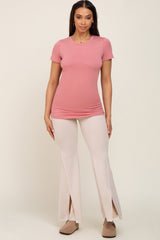 woman wearing a pink short sleeve top and beige flare pants with side slits