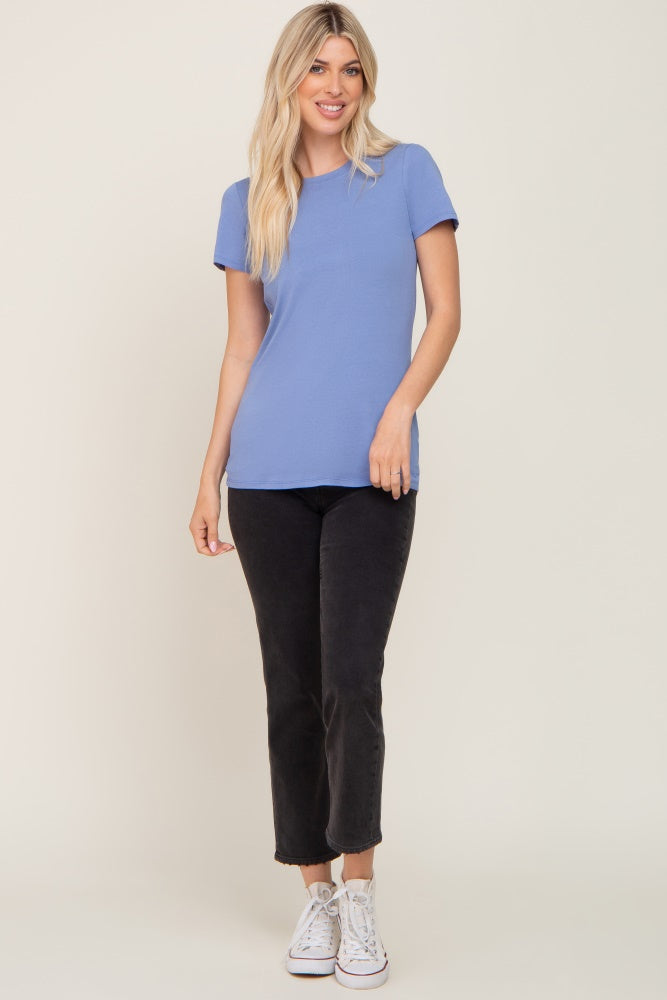 woman wearing a light blue short sleeve top and black cropped pants with white sneakers