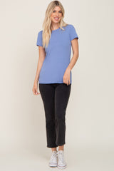 woman wearing a light blue short sleeve top and black cropped pants with white sneakers