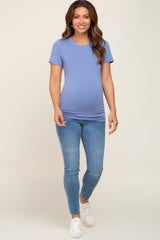 woman wearing a light blue maternity t-shirt and fitted jeans, showing a baby bump