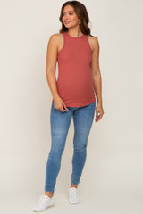 woman wearing a rust-colored ribbed maternity tank top and blue skinny jeans, showing her baby bump
