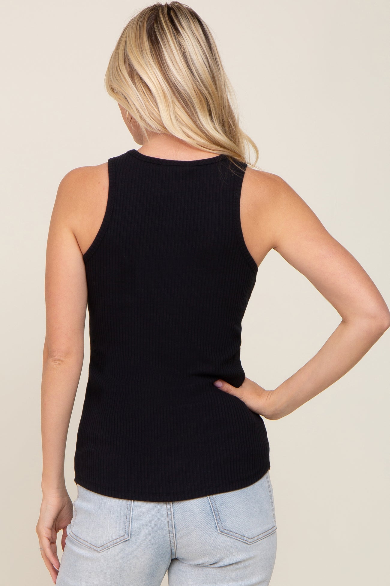 woman wearing a black ribbed sleeveless tank top, seen from the back, paired with light blue jeans
