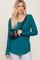 woman wearing a teal long sleeve ribbed top with a scoop neckline and styled with a black crossbody bag