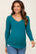 woman wearing a teal long sleeve maternity top with a scoop neckline and a visible baby bump