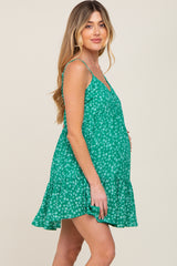 pregnant woman wearing a green floral maternity mini dress with spaghetti straps and a ruffled hem