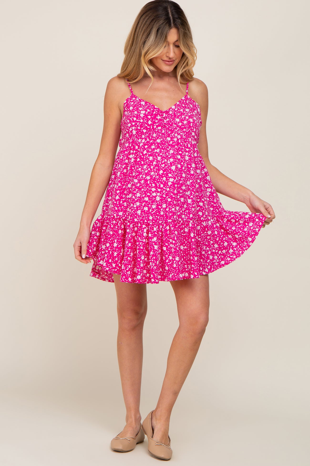 woman wearing a pink floral maternity mini dress with spaghetti straps and ruffled hem