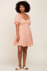 woman with afro hair wearing a pink floral puff sleeve mini dress and woven sandals