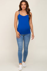 woman wearing a bright blue maternity tank top and light blue skinny jeans with a visible baby bump