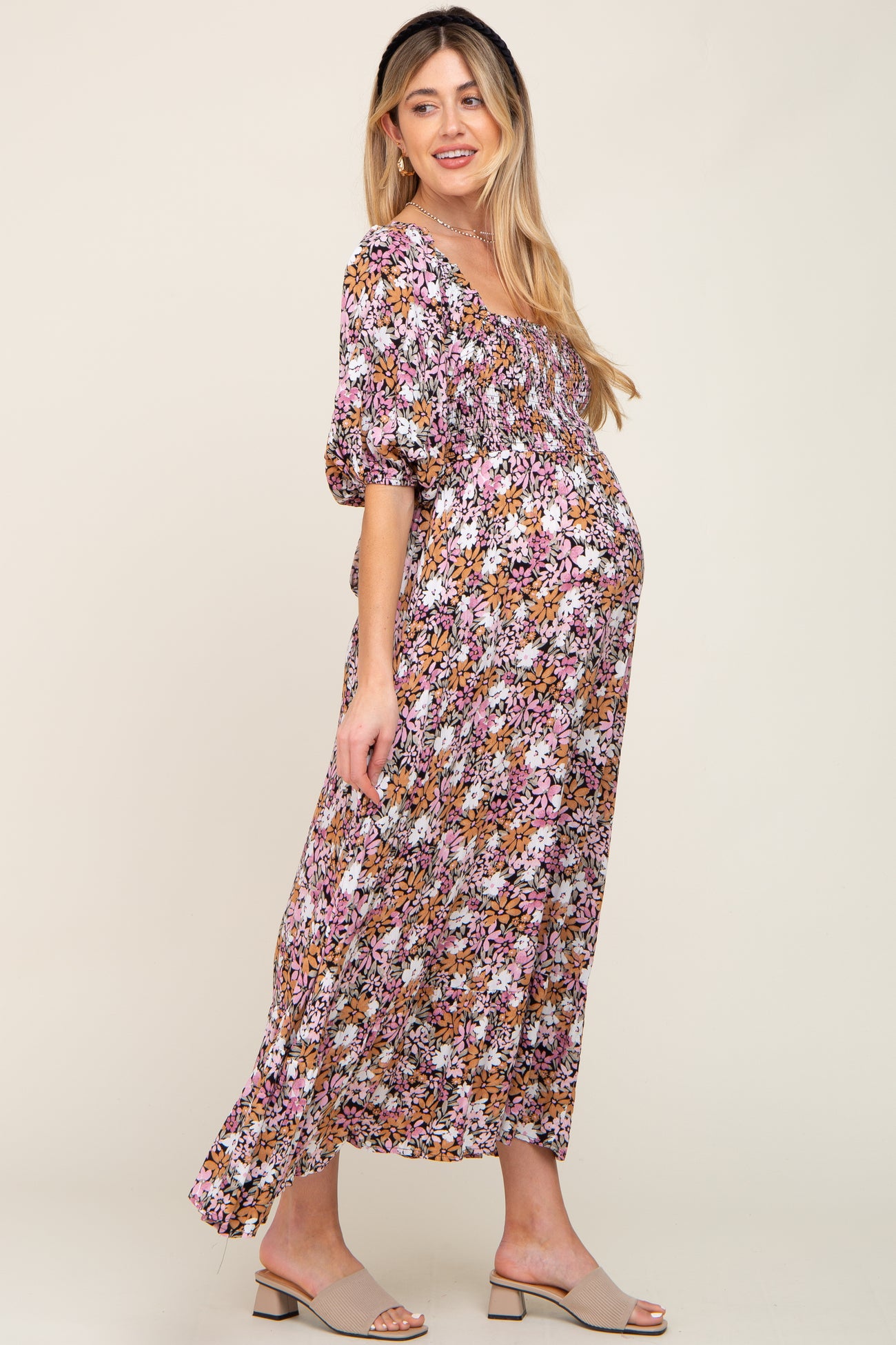 Pregnant woman wearing a floral smocked maternity maxi dress with puff sleeves and tan block heel sandals